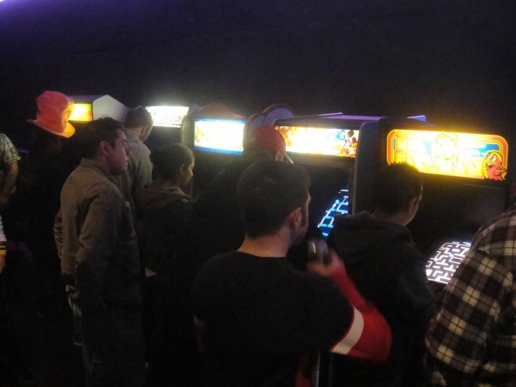 Vintage upright arcade cabinets lined up at a pop culture event