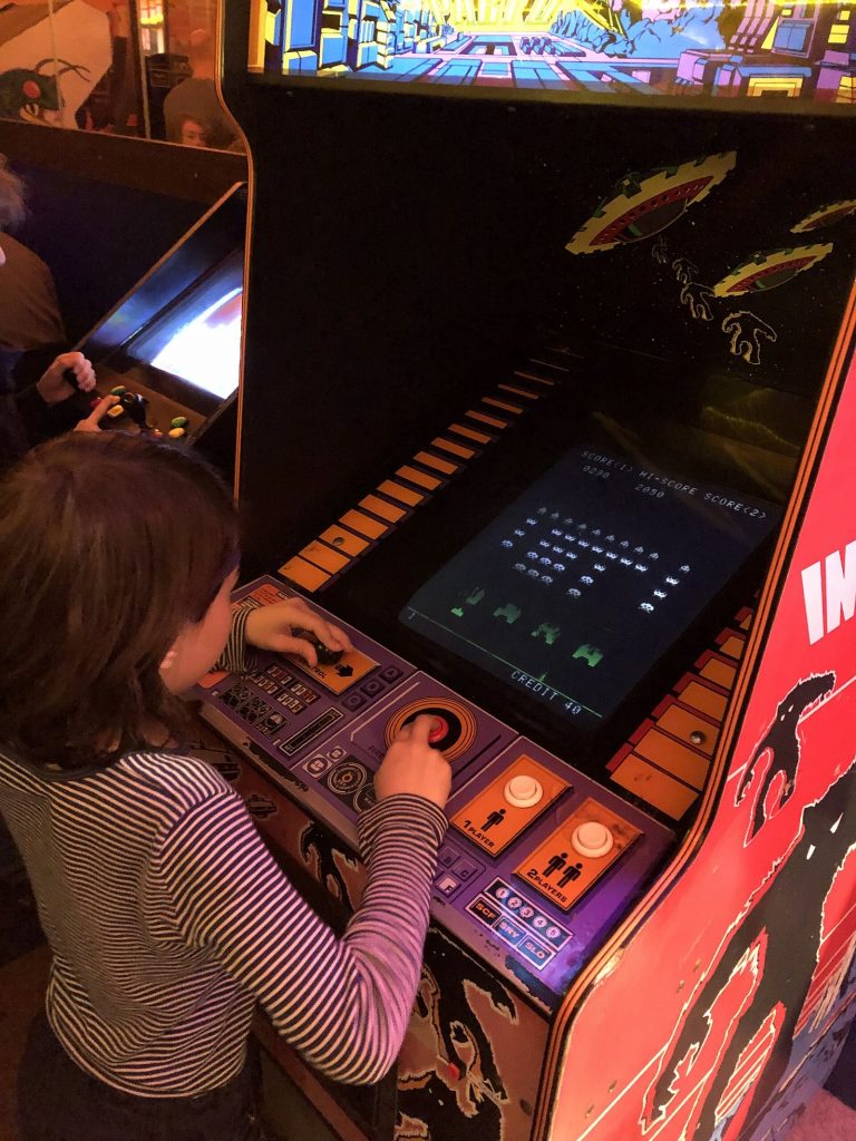 A girl playing a Space Invaders cabinet in a Berlin museum