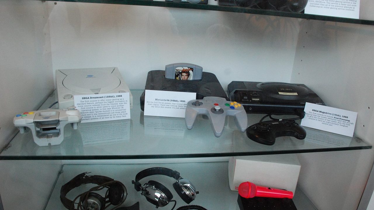 Rows of video game consoles from several eras on display at a museum exhibition